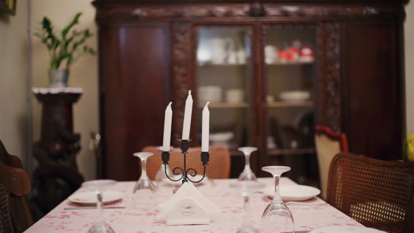 Dining table set with plates, glasses, and white candles in a cozy home interior