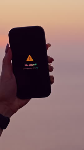 Vertical video. Silhouette Woman Raising Smartphone Searching for Signal at Ocean Cliff during Sunset with Bright Sun and Island Horizon Showing Connectivity Challenge in Remote Travel Adventure.