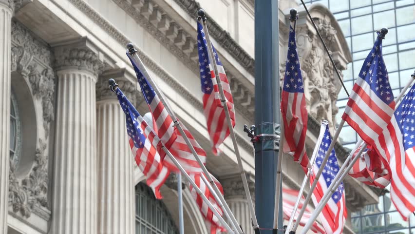 American flags near Grand Central Terminal on 42 street, New York City, Manhattan Midtown. Railway building architecture in United States. Public railroad transport junction. Old station exterior.