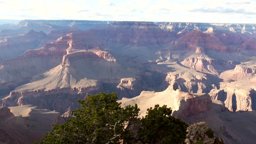 Stunning panoramic view of the grand canyon as beautiful sun rays and shadows from moving clouds sweep across the immense and layered red rock formations in this iconic arizona landmark