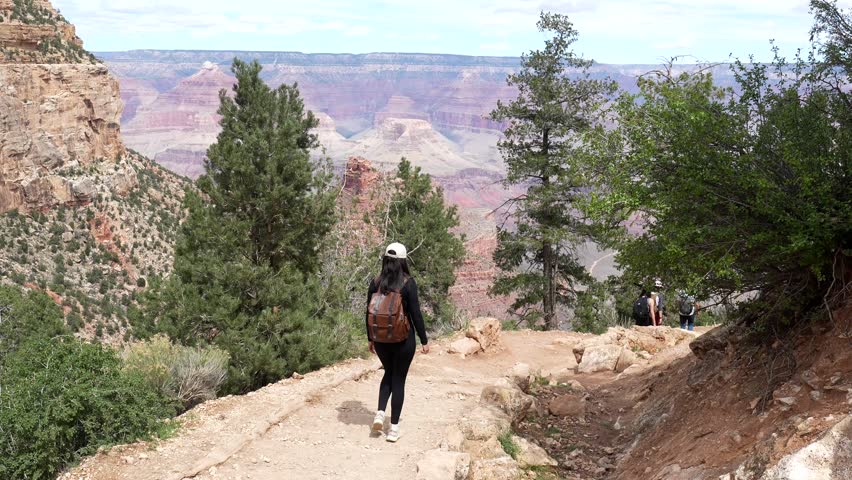Young athletic woman with a backpack hiking down the scenic bright angel trail during a beautiful day at grand canyon national park, an iconic american landmark in arizona, usa