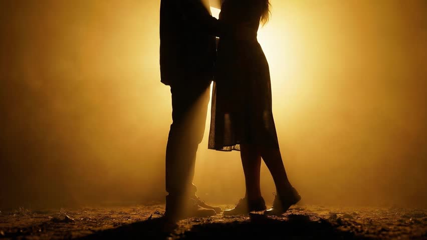 Romantic couple embracing in silhouette with warm backlight