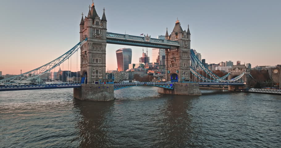 Tower Bridge, a historic bascule and suspension bridge, connecting boroughs over the River Thames with the city skyline illuminated by the setting sun. Aerial view drone shot of modern London city