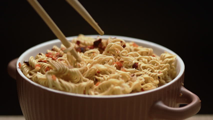 Asian fast food noodles in boiling water with spices, close-up. instant ramen soup eating with chopsticks.