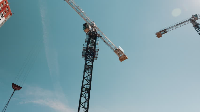 Two tower cranes above construction site against clear sky low angle view