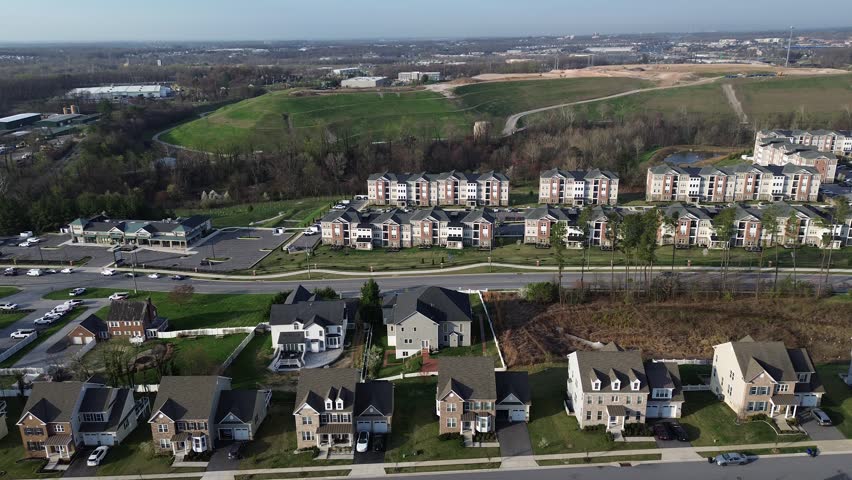 Hillside residential span captures aligned homes near Straw Lily Way with midrise apartments open green slopes extending toward White Marsh commercial edge, Maryland. USA