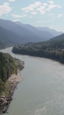 Aerial View of a Serene River Flowing Through Majestic Mountains in British Columbia, Canada