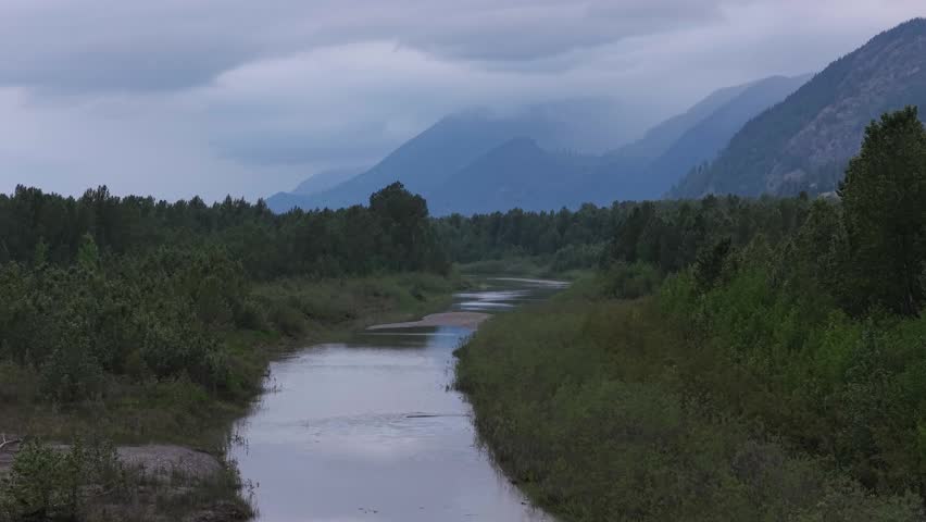 Aerial View of a Serene River Winding Through Dense Forests and Majestic Mountains in British Columbia, Canada