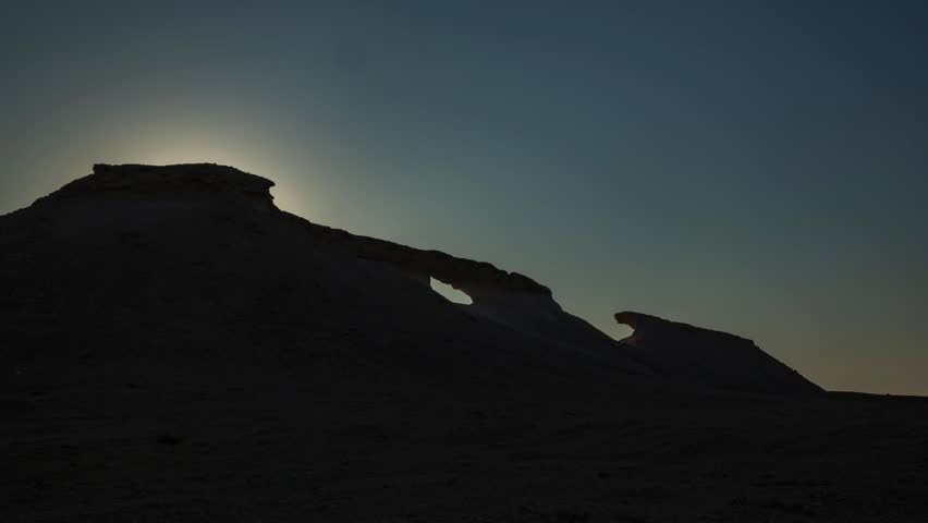 Traveling shot revealing dramatic desert rock formations in Zekreet, Qatar, with changing sunlight and arid landscape scenery