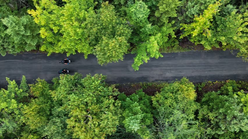Aerial Top View of cyclists on forest trail near lake in Nova Scotia Canada. Summer greenery and natural scenery create peaceful outdoor sport and travel atmosphere