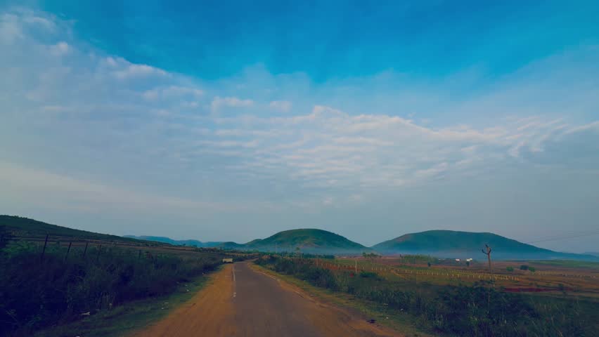 Beautiful landscape of green hills under a vast blue sky with white clouds at dawn and Scenic highway road passing through mountains and fields under a cloudy blue sky.
