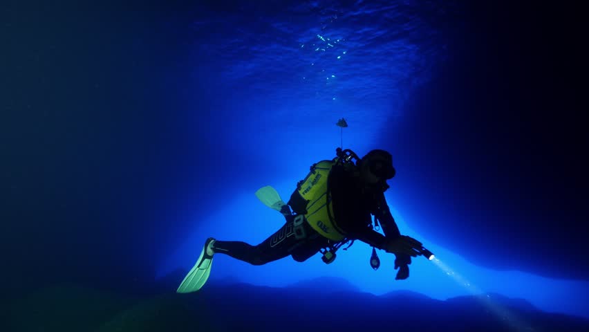 scuba divers are starting a cave dive underwater