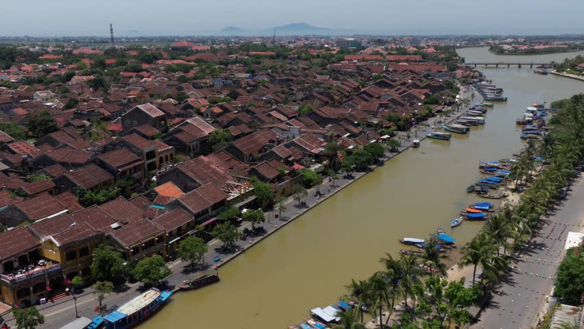 Top down aerial view of the iconic yellow walls and red terracotta roofs in Hoi An ancient town, Vietnam on a bright sunny midday.