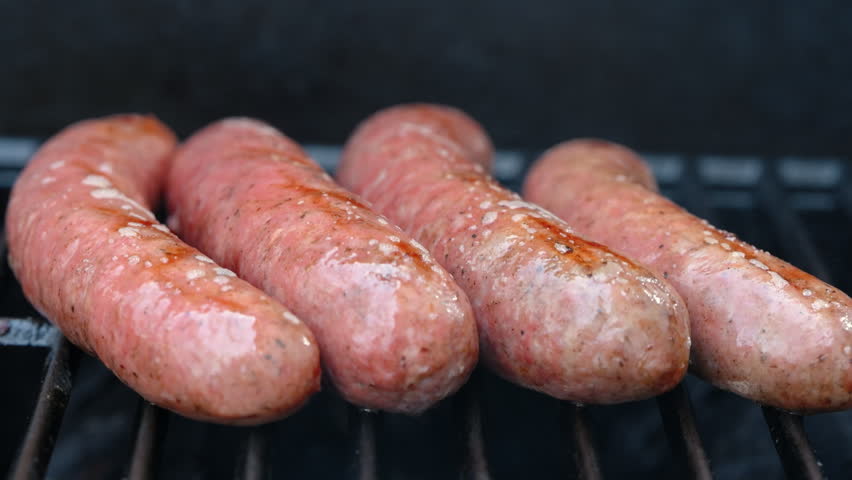 View of meat sausages grilling on barbecue with open flame. Close up of juicy meat cooking on grill, outdoor food and summer barbecue
