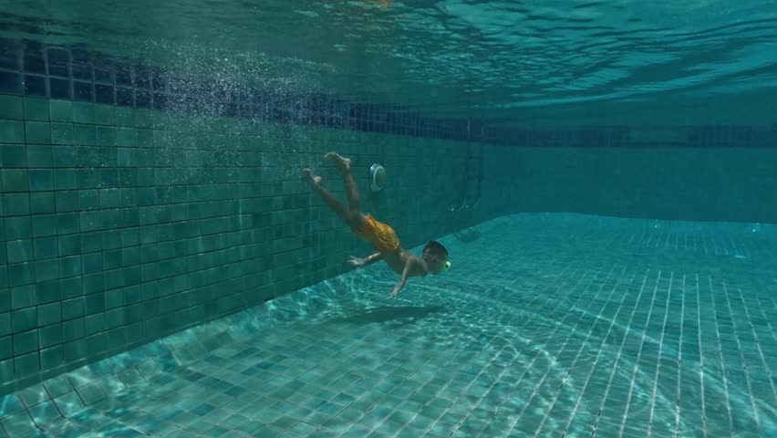 Cute Kid Dives in the blue water Pool.