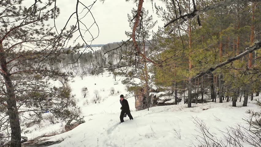Caucasian Hiker Climbing Snowy Slope, Pine Forest Backdrop, Valley View, Slow Determined Ascent, Heavy Jacket And Beanie, Crunching Footsteps, Overcast Winter Light, Solitude