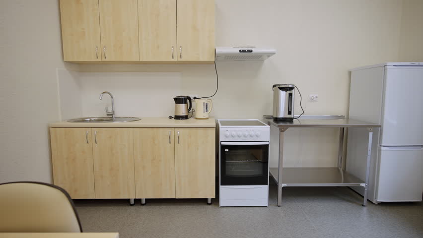 Functional kitchen corner features stove sink and storage cabinets. Minimalistic space equipped for simple cooking during class time
