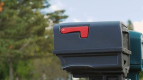 Woman puts paper mail in a mailbox on a sunny day. Person sending a letter into a mailbox. Female hand putting a message into a modern mailbox. Cinematic slow-motion footage of mail delivery. - Powered by Shutterstock - Get 15% off with code: PIKWIZARD15