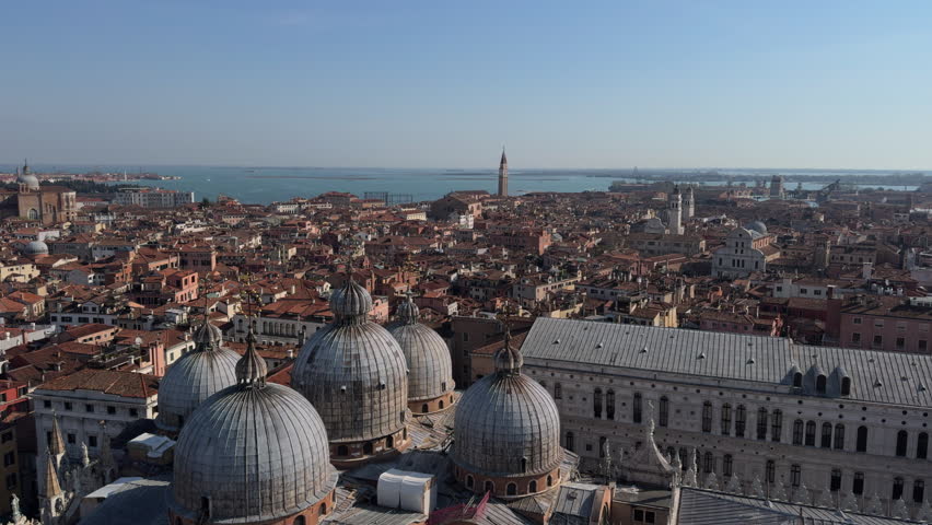 A panoramic view of Venice shows domes, canals, bridges, and the sea under soft light, creating a calm, melancholic atmosphere.