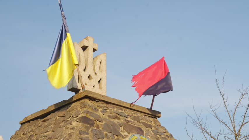 Close up of Ukrainian memorial top with flags waving against clear sky background
