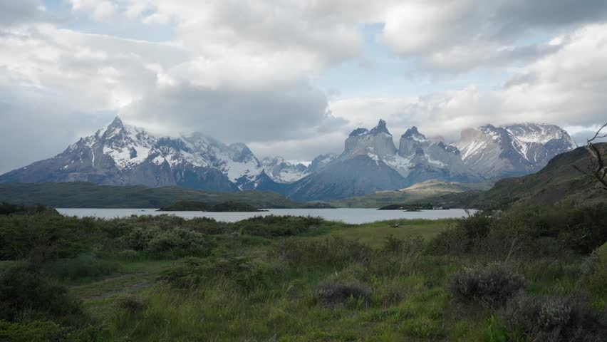 Wide landscape view showing the famous mountain massifs and a calm lake in the Torres del Paine National Park, Chile.