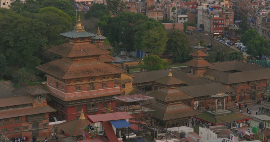 Drone shot of Patan Durbar Square in Lalitpur Nepal, UNESCO heritage site, traditional Newari palace architecture, Krishna Mandir, historic temples, ancient royal structure surrounded during sunset.