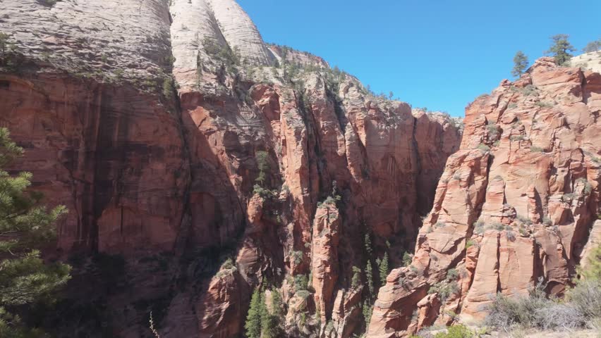 The stunning red rock cliffs of Zion National Park in a slow panning shot.