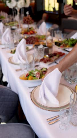 Long wedding banquet table with salads, fruit platters and crystal glasses as a guest reaches for a plate in a cozy indoor venue.