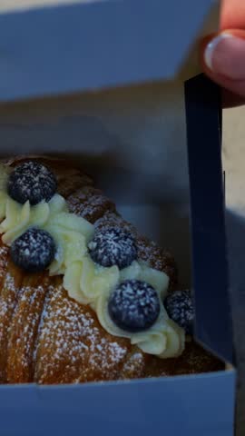 Decorative pastry with cream. Artful arrangement of blueberry croissant with garnish and swirl. Closeup of pastry stylist expertly plating blueberry croissant with cream and decorative garnish