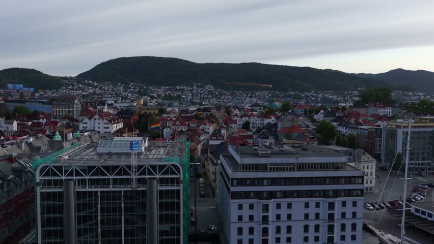 Wide aerial view of Bergen cityscape with mountains in background under cloudy sky, aerial
