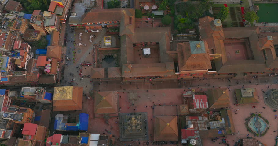 Drone top-down shot of Patan Durbar Square in Lalitpur, Nepal, UNESCO heritage site, with geometric layout of royal courtyards, temple rooftops, historic Malla palace architecture and public activity.