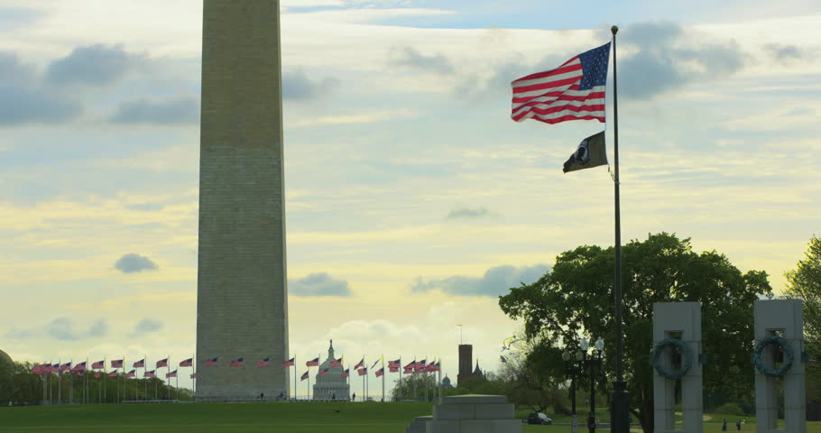 American Flag and Washington Monument against Colorful Sky with US Capitol Dome in Distance