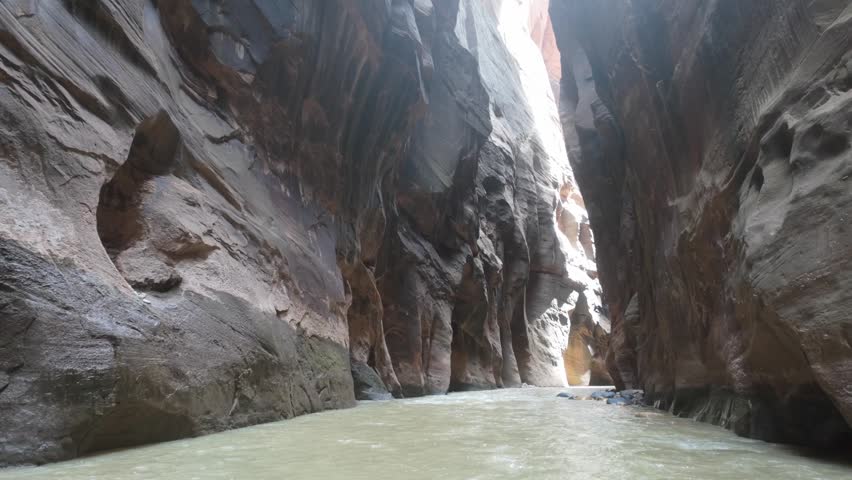 A river runs through the towering walls of The Narrows at Zion National Park.
