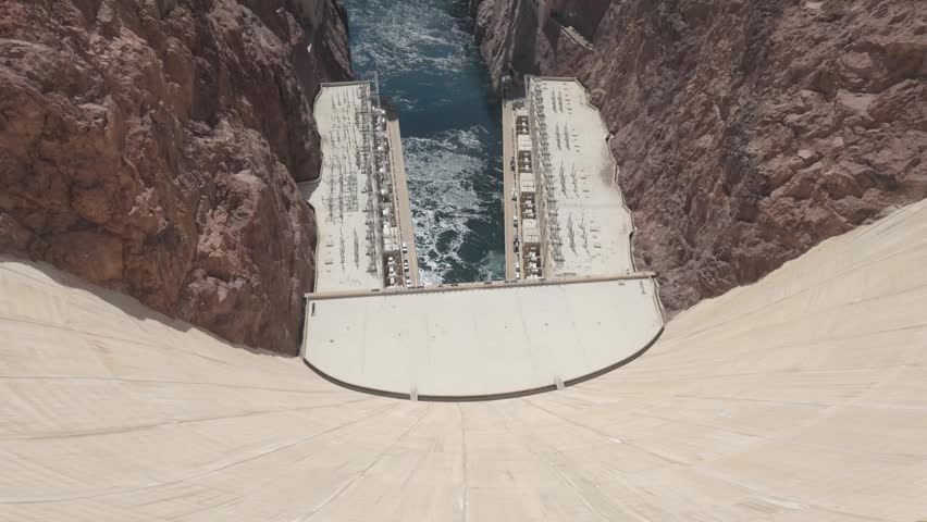 Looking over the edge of the Hoover Dam, showcasing the large drop to the base where the Colorado River emerges.