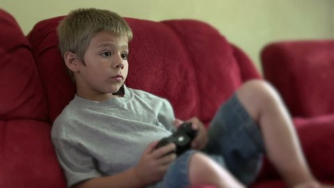 Child playing video game sitting on couch