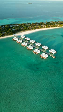 Maldives resort with island houses palm trees and overwater bungalow grid on turquoise lagoon
