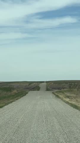 Scenic driver perspective along remote countryside gravel transportation route