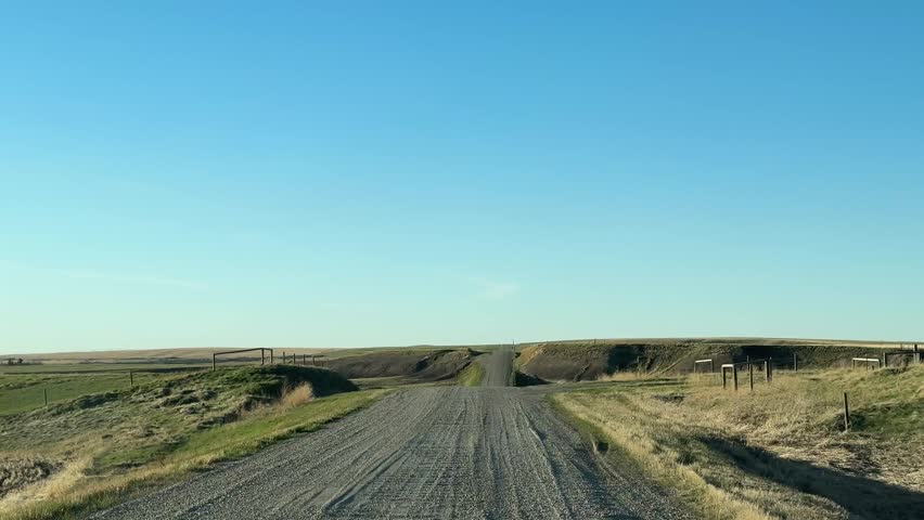 Traveling down rustic rural gravel roadway through open landscape