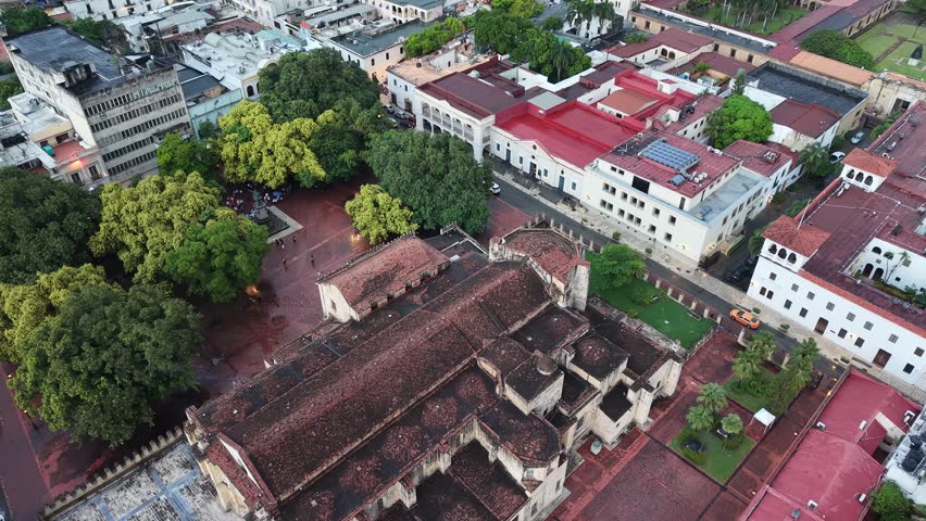 Aerial view of Columbus Park (Plaza Colon) and the First Cathedral of America in Santo Domingo. Cinematic drone shot featuring the Christopher Columbus statue and the historic colonial architecture.