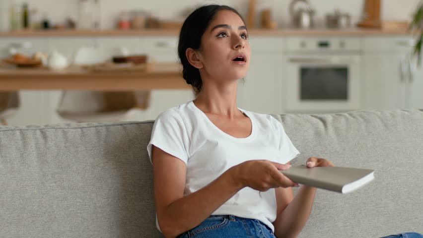 Overheated Indian Arabian woman at home waving notebook tired female sweating indoor suffering high temperature hot broken air conditioner lack of climate control discomfort studying girl heat problem