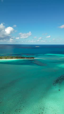 Maldives small island with white sand beach surrounded by turquoise shallow ocean water - aerial