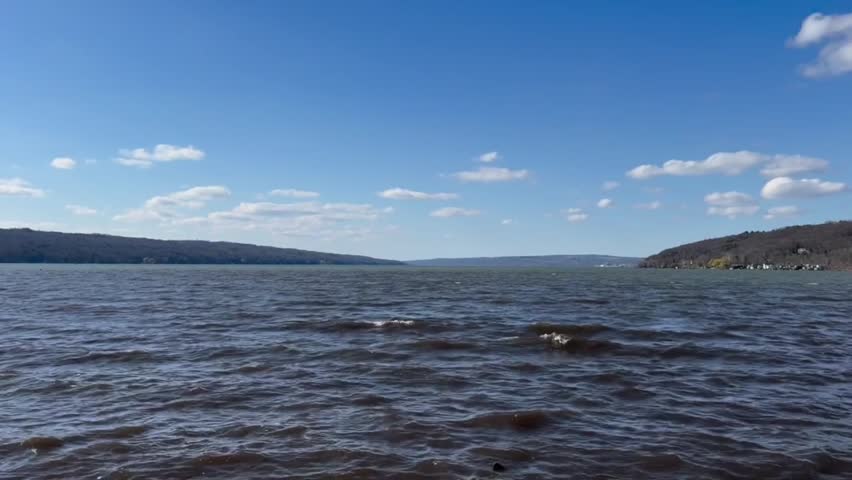 Wide blue lake water under a bright sunny sky with fluffy white clouds