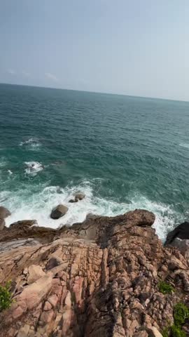 Rugged rocky cliff overlooking the blue ocean waves at the seaside