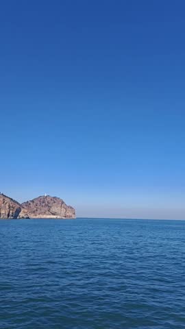 Rocky island in the deep blue sea under a clear sunny sky