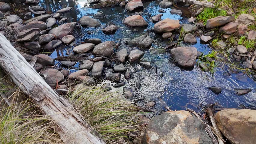 Static high-angle shot of clear water flowing through a rocky creek in New South Wales