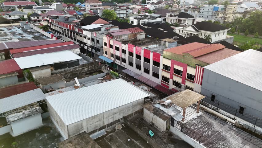 An aerial view showing a row of buildings and rooftops facing a narrow street, along with parked cars.
