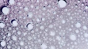 Abstract macro view of purple tinted soap bubbles and foam circles floating and moving slowly across a bright white background surface - Powered by Shutterstock - Get 15% off with code: PIKWIZARD15