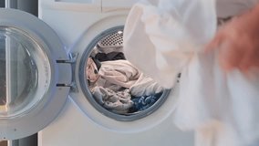 Woman placing white clothes into front load washing machine at home. Laundry routine, sorting light garments before washing, domestic chores, hygiene and everyday household cleaning process. - Powered by Shutterstock - Get 15% off with code: PIKWIZARD15