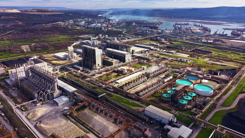 The scene shows various factories and water treatment plants in an industrial area beside a river. The setting is busy with many structures and machinery visible.