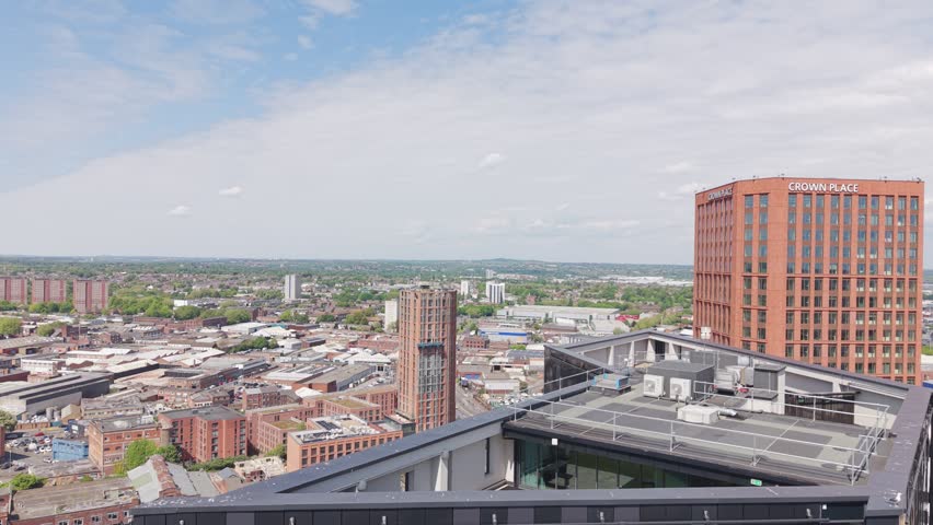 Smooth cinematic drone footage descending alongside a modern black residential tower in Birmingham UK. Urban skyline and contemporary city architecture visible in the background during the close aerial pass.